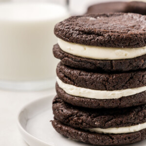 A stack of homemade Oreo cookies with a glass of milk.