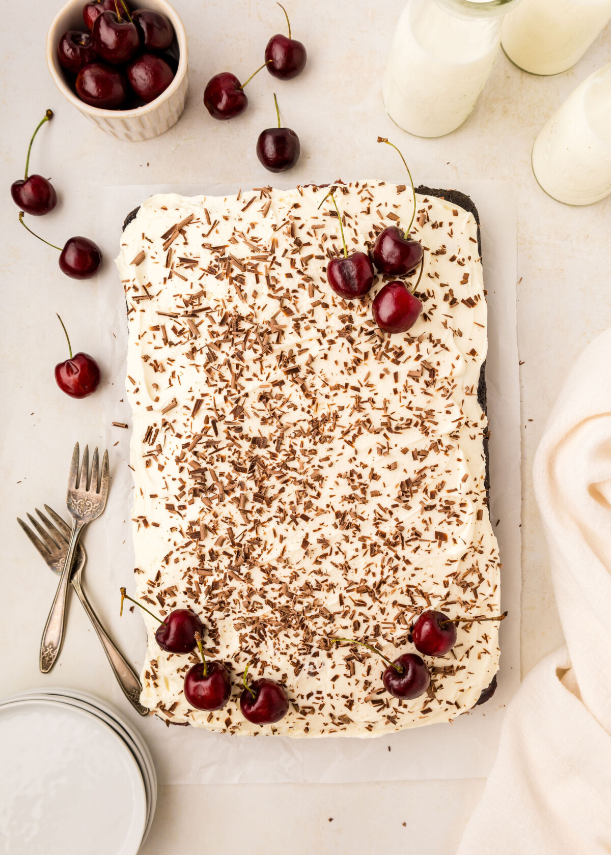 A Black Forest Poke Cake as a sheet cake with cherries and chocolate shavings.