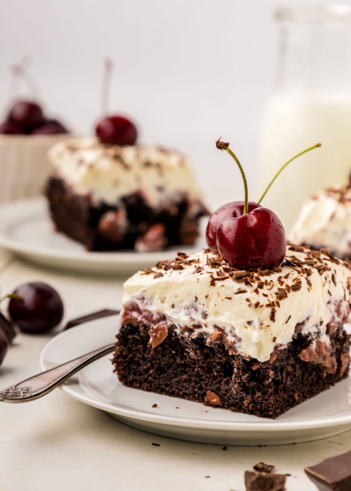 A slice of the best Black Forest Poke Cake on a white plate.