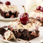 A slice of Black Forest Poke Cake with a fork on a plate.