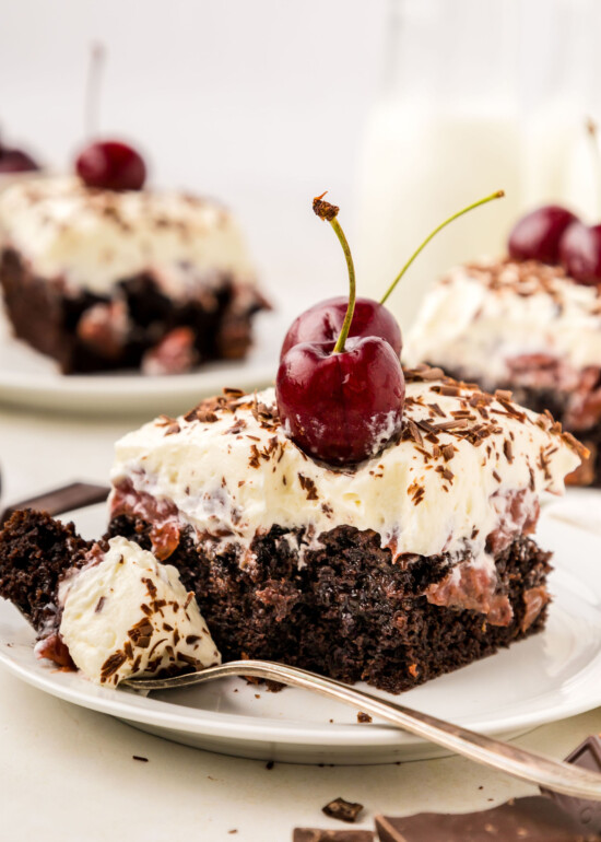 A slice of Black Forest Poke Cake with a fork on a plate.