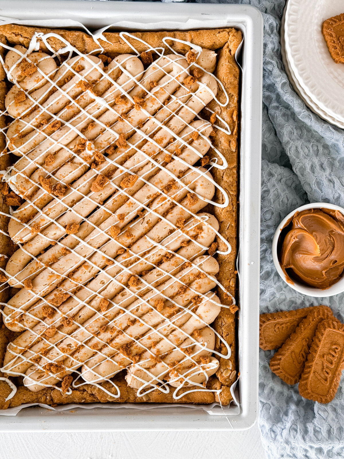 Biscoff blondies in a metal pan with a towel next to it.