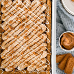 Biscoff blondies in a metal pan with a towel next to it.