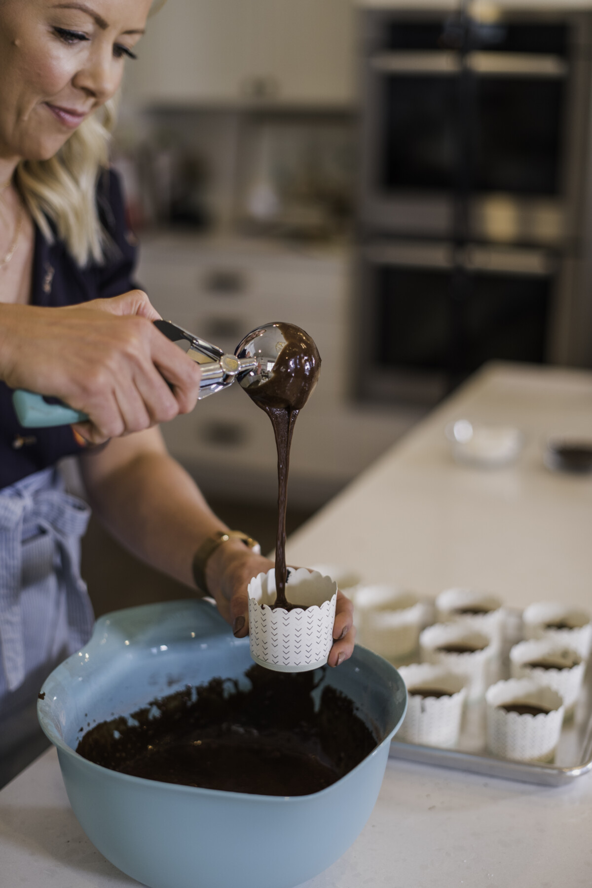 Woman putting cupcake batter into cupcake liners.