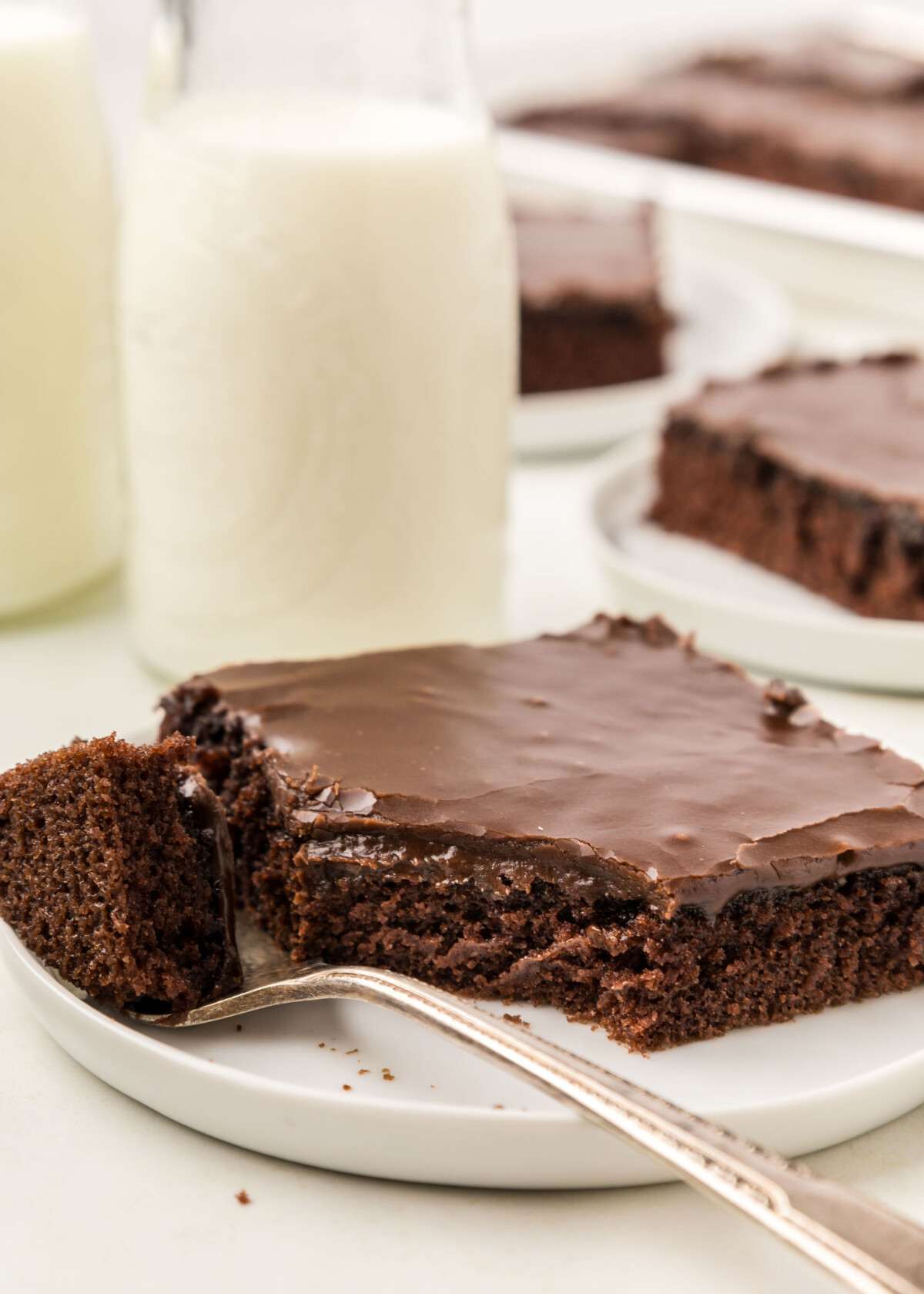 A slice of cake with a bite taken out of it with milk in a bottle.