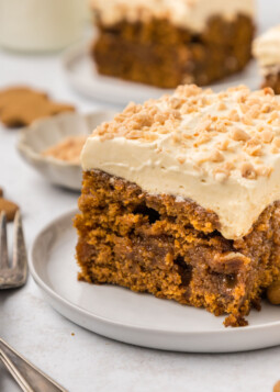 A slice of gingerbread poke cake on a plate with a fork.