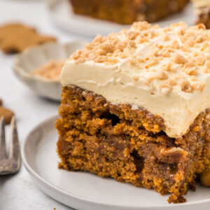 A slice of gingerbread poke cake on a plate with a fork.