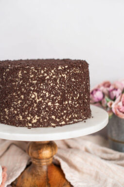 A chocolate cake with brown sugar buttercream on a cake stand.