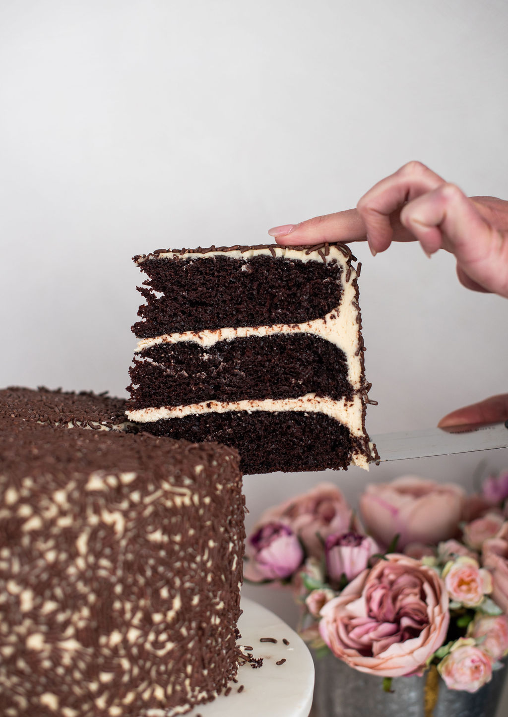 Someone taking a slice of cake out of a full cake.