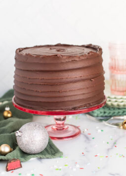 A chocolate cake on a pink cake stand.