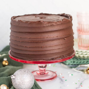 A chocolate cake on a pink cake stand.