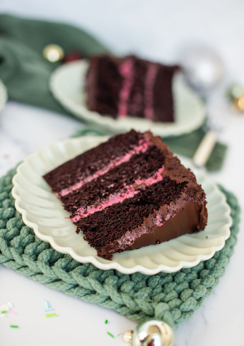 A slice of dark chocolate cake with raspberry cream filling on a green plate.