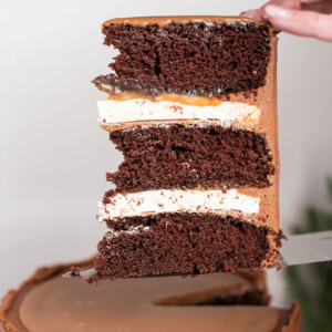 A slice of chocolate cake being held on top of a knife.