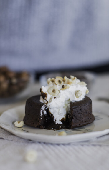 Chocolate lava cake on a plate with chocolate spilling out of the center.