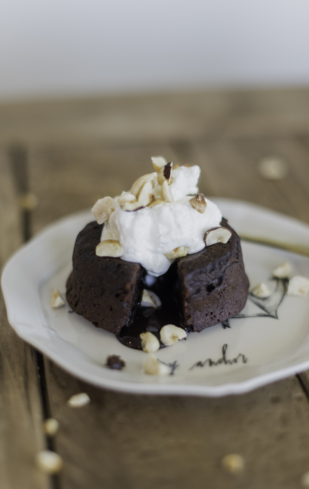 A plate of chocolate lava cakes with molten centers, garnished with whipped cream and hazelnuts.