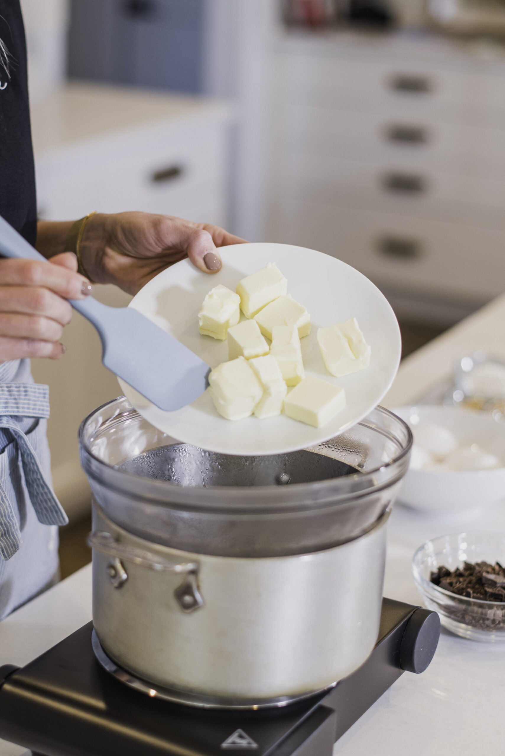 A woman melting butter in a double broiler.