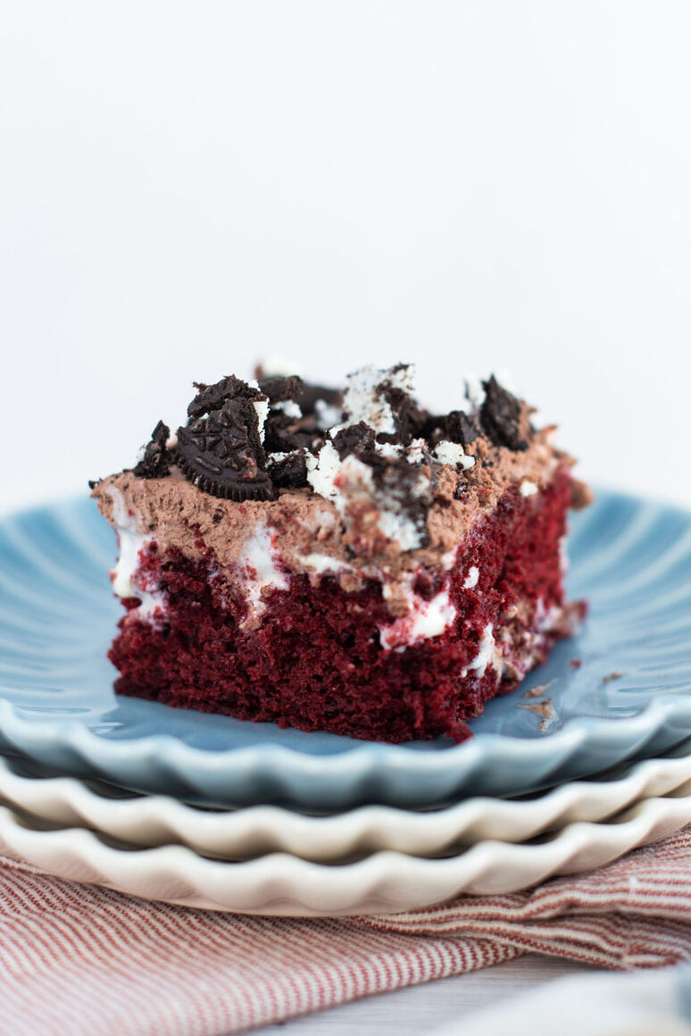 a slice of red velvet Oreo poke cake on a stack of plates.