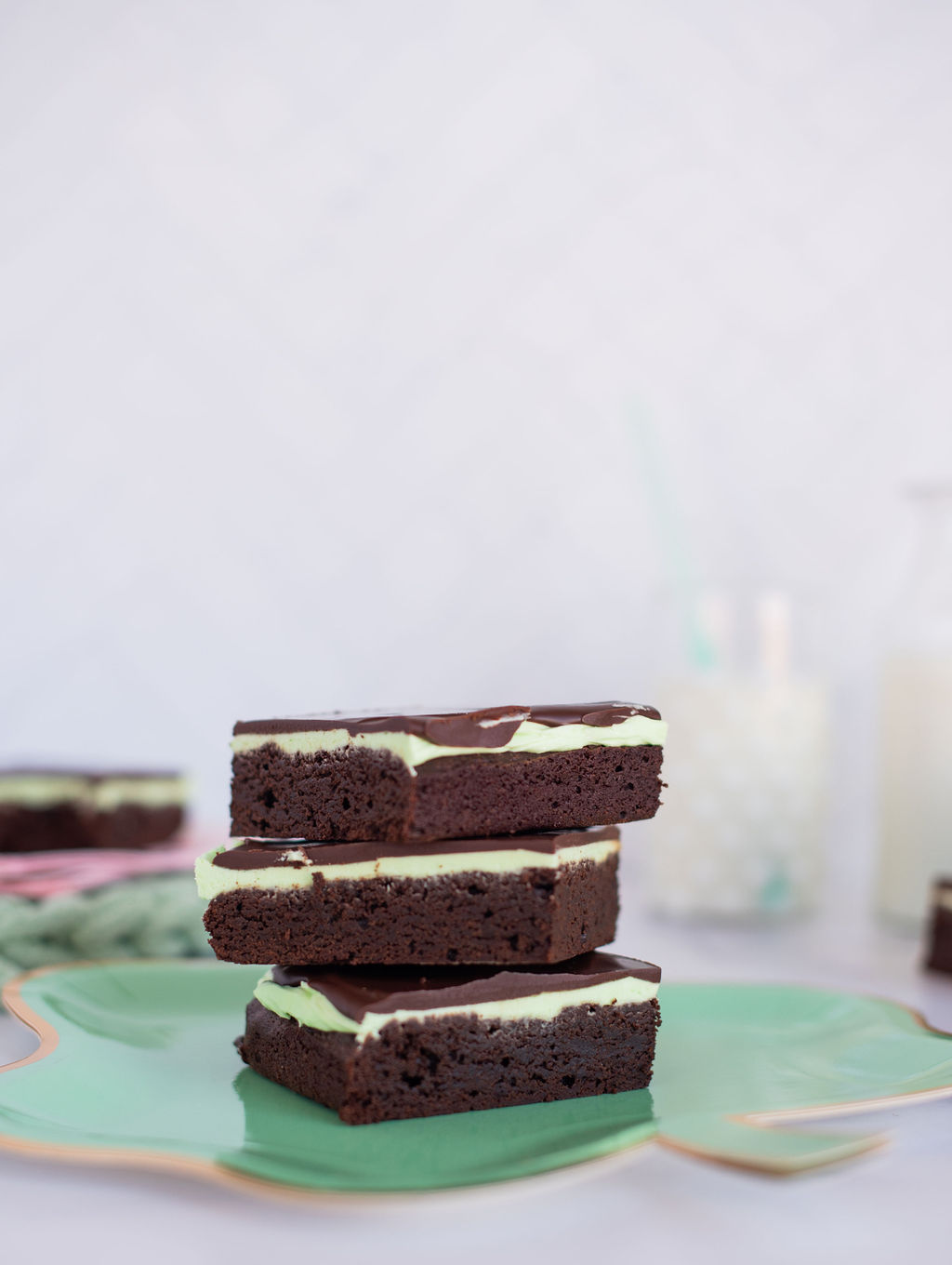 A stack of three mint brownies on a green four leaf clover plate.