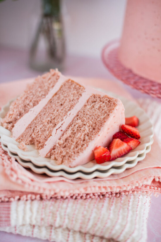 A slice of strawberry cake on a plate with pink napkins.