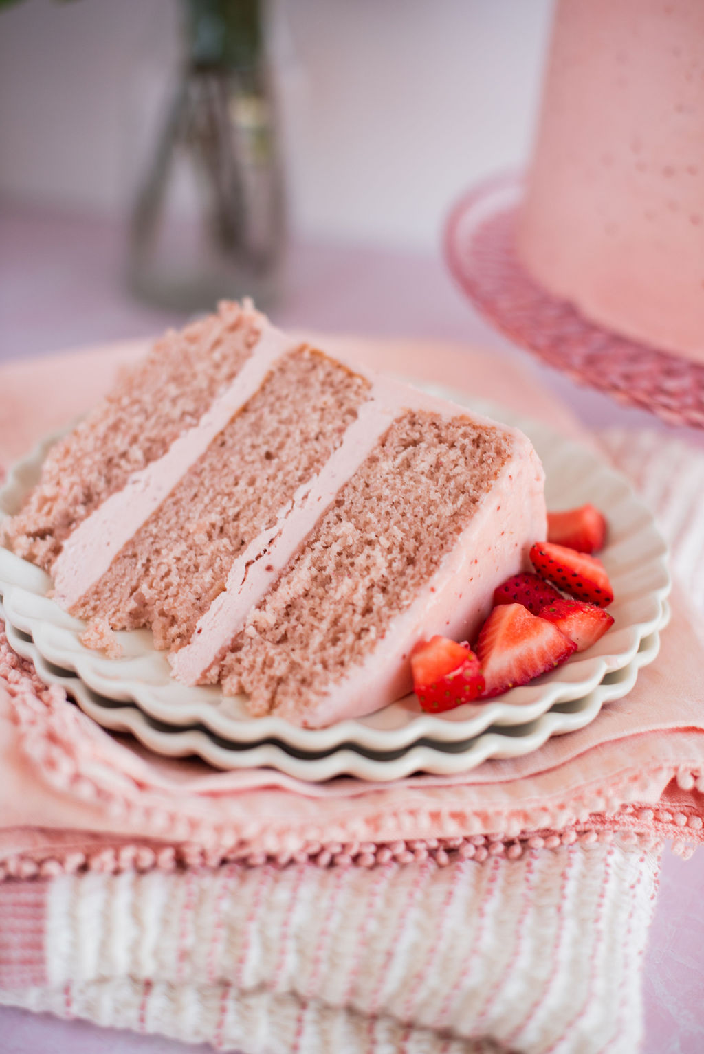 A slice of strawberry cake on a plate with pink napkins.