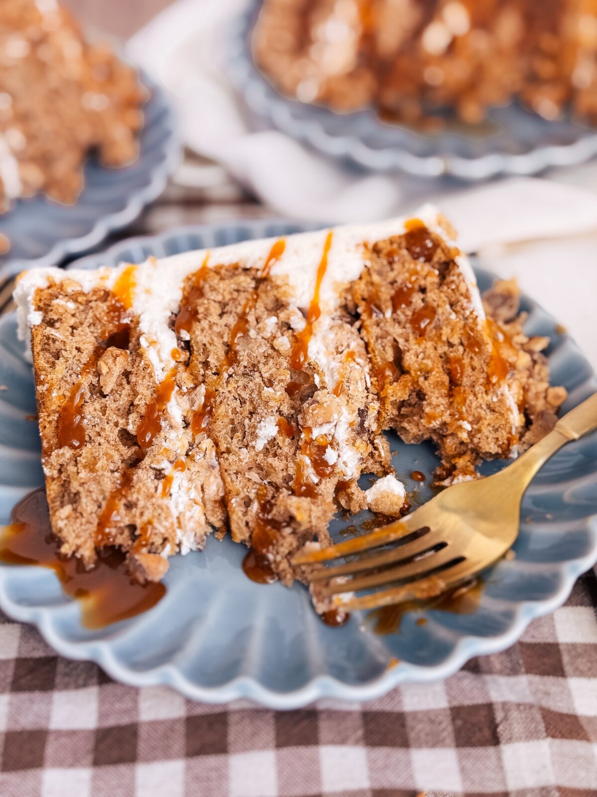 A slice of cake with caramel drizzled on top on a blue plate.
