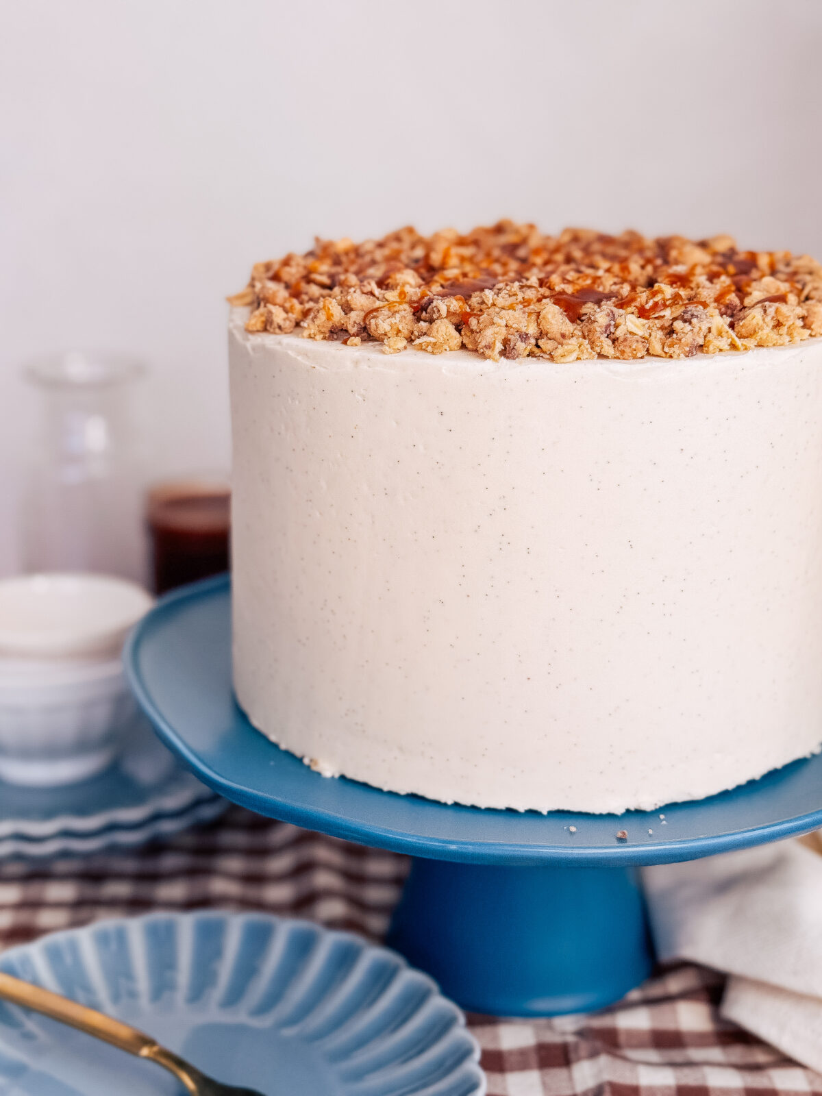 A cake with vanilla buttercream and cookie dough on a blue cake stand.