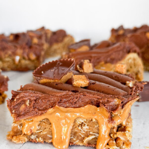A peanut butter blondie bar with peanut butter dripping and chocolate buttercream.
