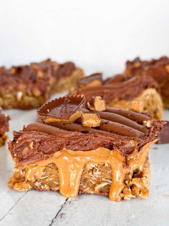 A peanut butter blondie bar with peanut butter dripping and chocolate buttercream.