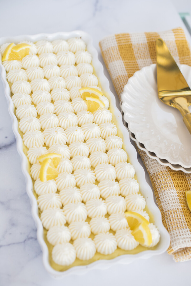A lemon tart in a white dish with a plate next to it.