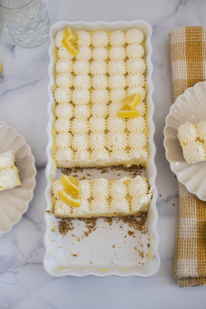 A lemon tart in a white dish with a few slices taken out.