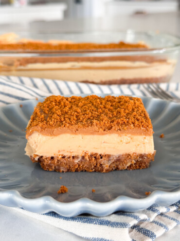 A slice of no-bake Biscoff Cheesecake Bars on a blue plate.