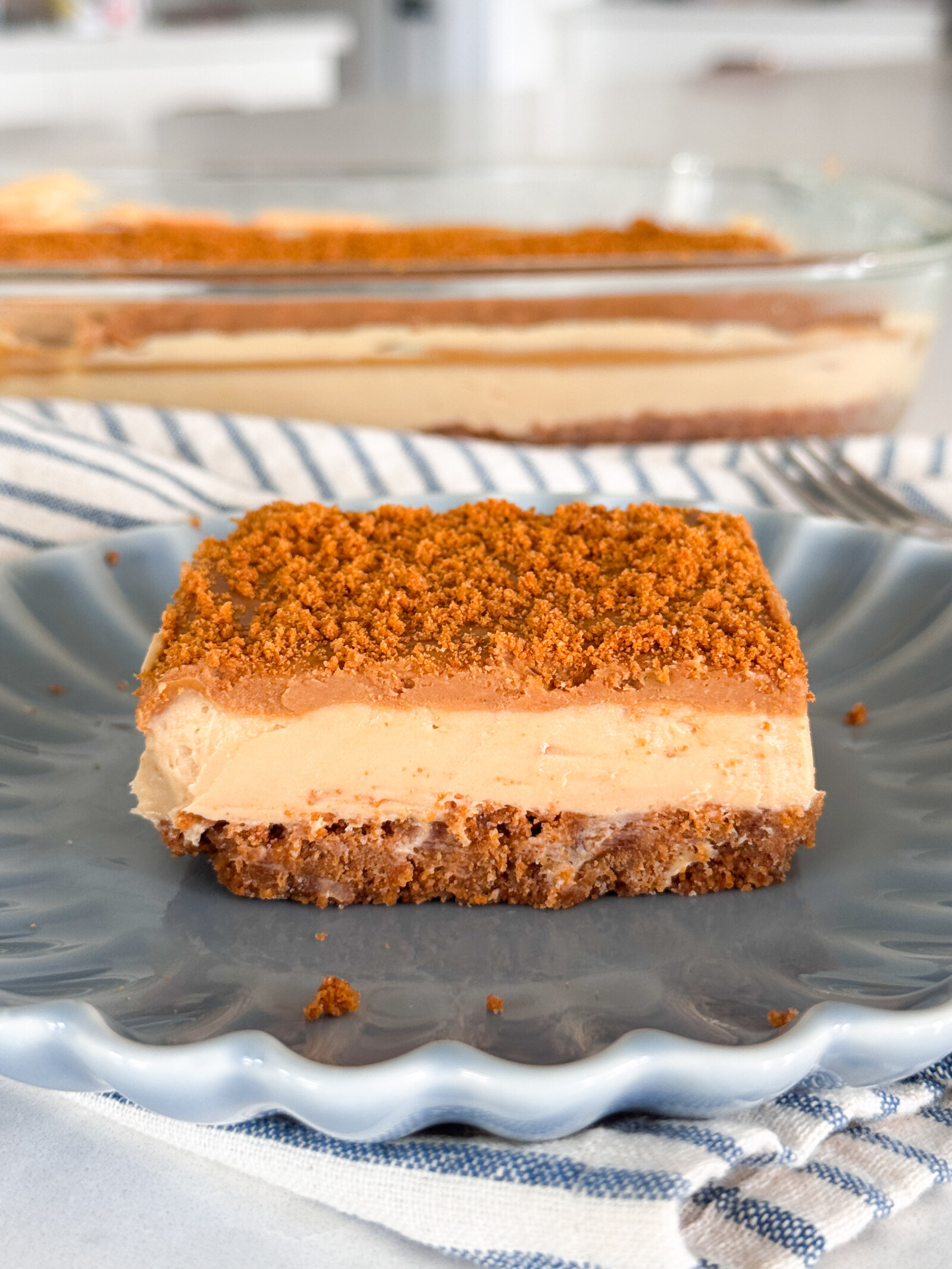 A slice of no-bake Biscoff Cheesecake Bars on a blue plate.