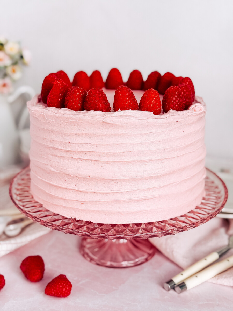 Raspberry Cheese Danish Cake on a pink cake stand with raspberries on top.