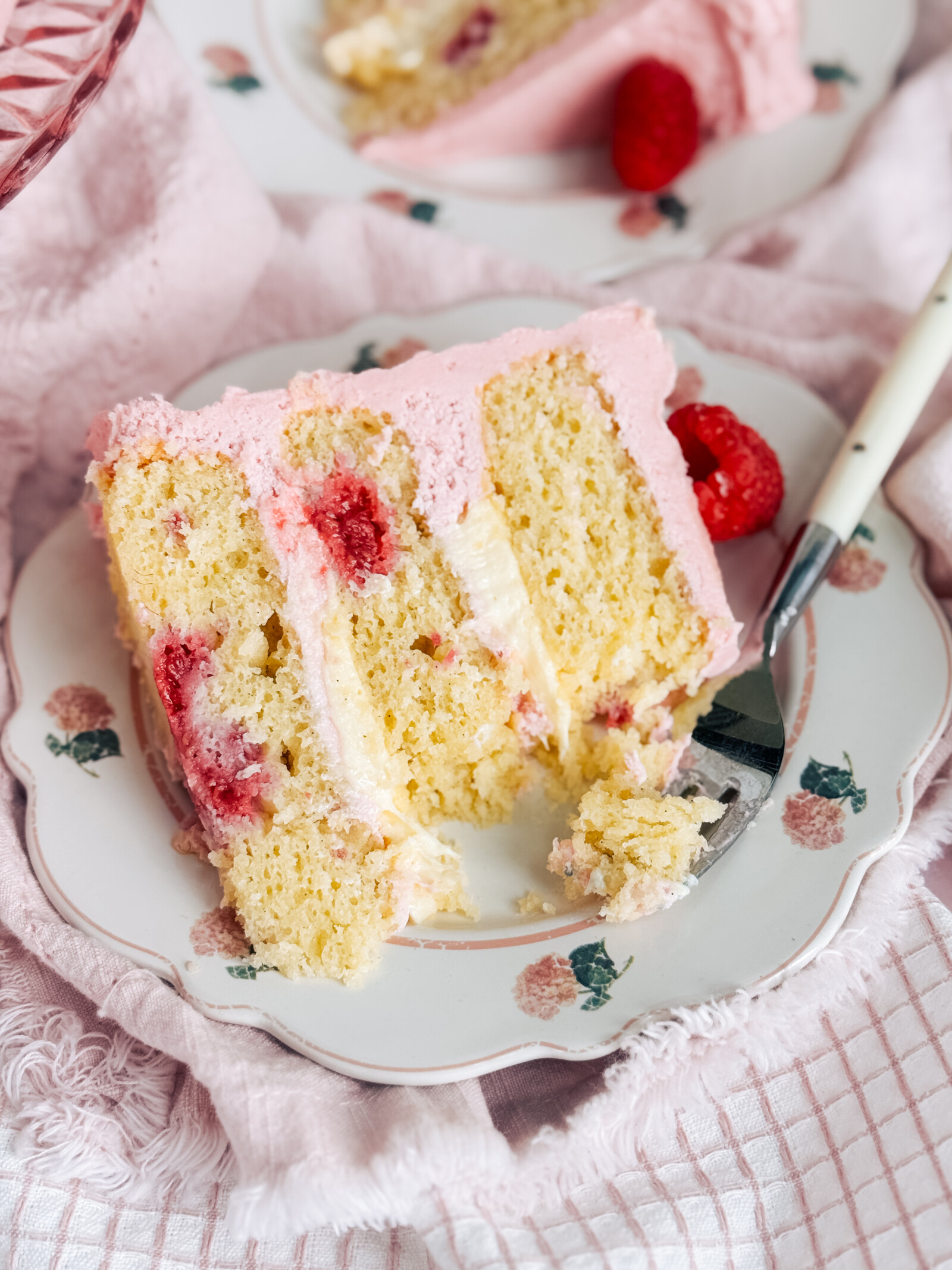 A slice of raspberry cheese danish cake on a floral plate with a fork.